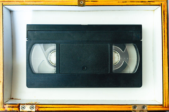Flat lay photography of a black VHS video cassette inside a wooden box