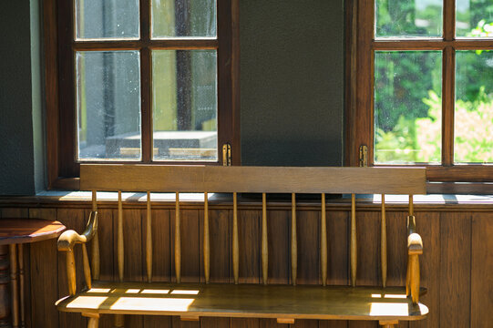 Wooden Indoor Bench with Backrest Positioned Beneath Large Windowpane