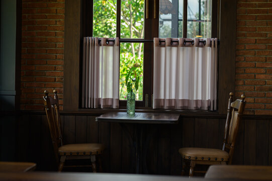 Cozy Window Scene with Bright Natural Light, Curtain, Greenery, and Wooden Chairs