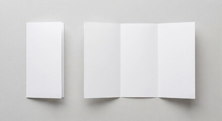 Naklejka premium Top-down view of white folded and unfolded brochures on a neutral light gray background with soft lighting.