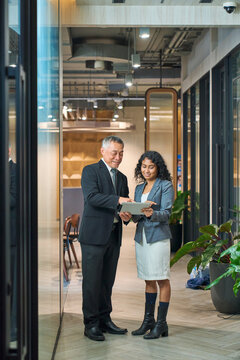 Senior Asian Executive Mentoring Young Colleague with Digital Tablet in Modern Office.