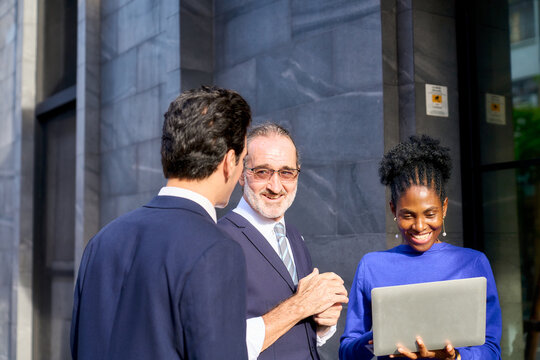 Diverse Professional Team Collaborating with Laptop Near Modern Office