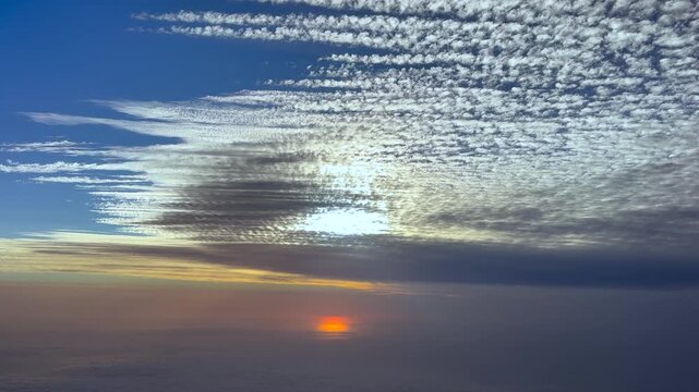 A left side cockpit view of a sunrise over the Mediterranean sea of a layer of parallel altocumulus clouds