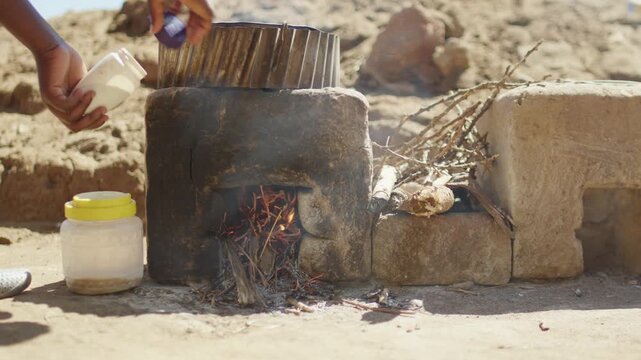 African woman making African tea on a traditional African Cooker