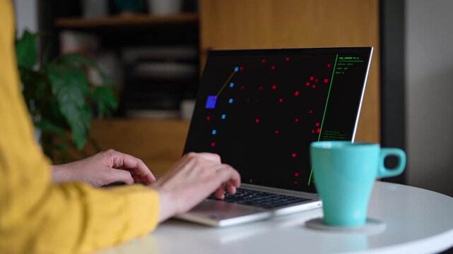 Woman playing retro arcade video game on laptop.