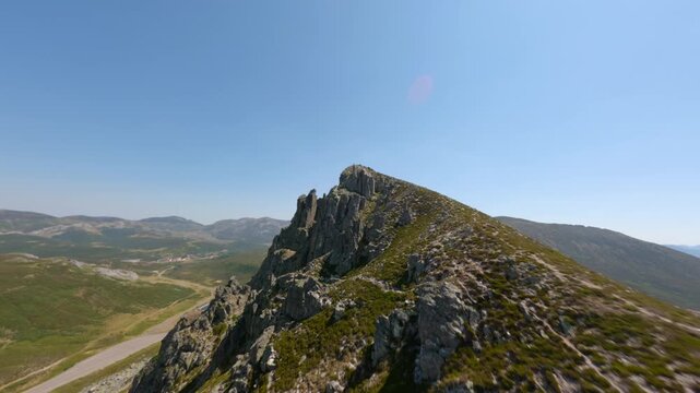 Dynamic FPV drone video soaring over rugged rocky ridgeline in Puerto San Isidro, Cordillera Cant&aacute;brica. Bright clear sky, panoramic landscape, epic sunlight, sweeping aerial movement.