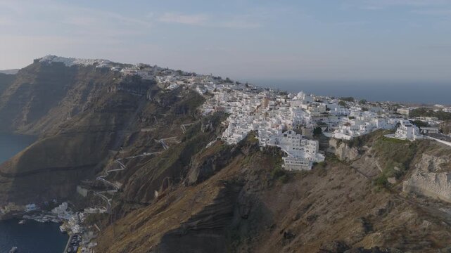 Aerial view of Fira, Santorini, perched above the caldera with the famous zigzag switchback path winding down the cliff to the old port below.