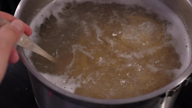4K slow-motion video of boiling and stirring fusilli pasta in a pot