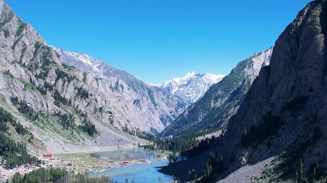 River flows through Upper Ushu Valley beneath snowcapped Hindu Kush peaks, Khyber Pakhtunkhwa, Pakistan