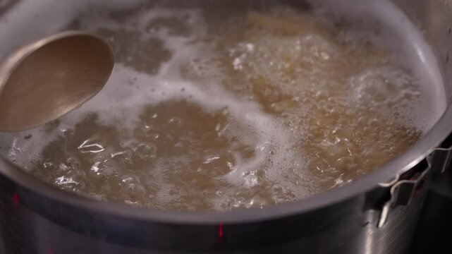 4K slow-motion video of boiling and stirring fusilli pasta in a pot