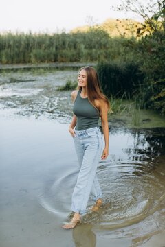 Young woman walking barefoot in river enjoying summer day