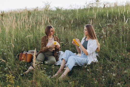 Two women peeling corn enjoying outdoor picnic
