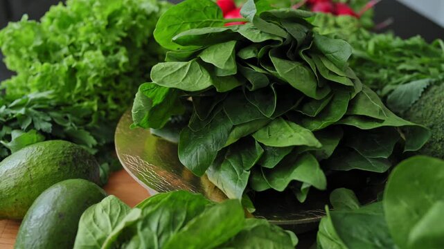 Fresh spinach leaves rotate on golden podium next to lettuce, broccoli, radishes, avocado, parsley, and dill. Organic vegetables and leafy greens for healthy diet. Farm produce. Bunch of spinach. 4k