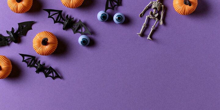 Halloween Flat Lay Background with Pumpkins Bats Spiders and Skeletons on Purple Surface