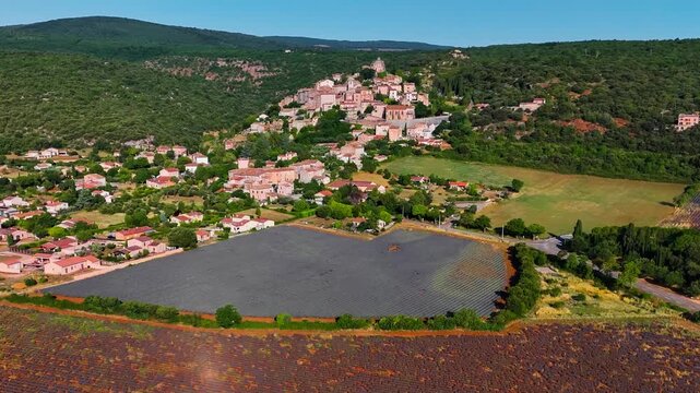 Aerial drone view Simiane-la-Rotonde among the mountains and blooming purple lavender fields. Provence-Alpes-Cote d'Azur region. High quality 4k footage