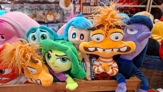 Colorful Disney Pixar Inside Out character plush toys including Anxiety Disgust Joy and Ennui sitting together in wooden crate display at store shelf on July 3, 2026 in Bangkok, Thailand.