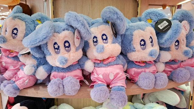 Row of cute pastel blue Mickey Mouse plush toys wearing pink shorts sitting on wooden retail store shelf on June 2, 2026 in Bangkok, Thailand.