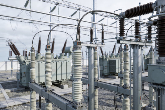 High voltage electrical substation with transformers and insulators under a cloudy sky