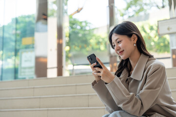 Fototapeta premium Beautiful business woman using mobile phone work in business buildings. Smart female using cell phone chatting for business communication talking. Business lifestyle concept.