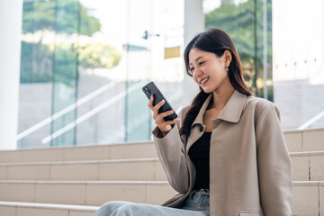 Fototapeta premium Beautiful business woman using mobile phone work in business buildings. Smart female using cell phone chatting for business communication talking. Business lifestyle concept.