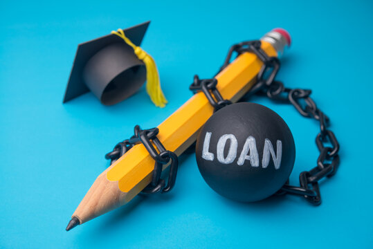 Mortarboard and pencil with heavy loan on blue background. Student loan or student debt non payment, delinquent, bad credit score, personal financial crisis, education and so on concept.