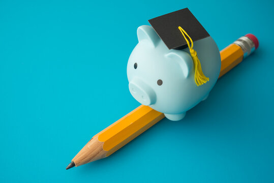 Piggy bank with mortarboard riding pencil on blue background. Education, money savings and financial planning for education in university, college or study abroad, scholarship and so on concept.
