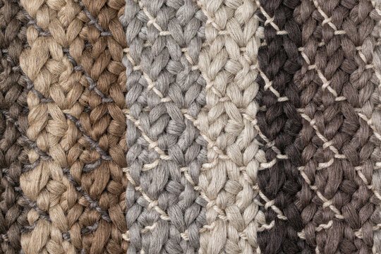Close up macro view of a woven textile fabric with a thick braided pattern in alternating vertical stripes of brown, grey, and beige