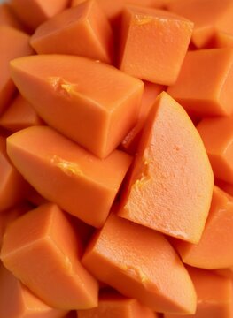 Fresh ripe papaya chunks background with detailed tropical fruit texture