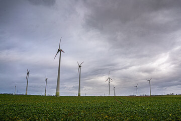 Wind turbines on a green field under a blue cloudy sky generating renewable energy. © Marcel