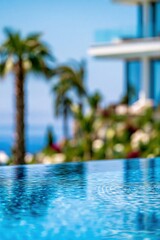 Fototapeta premium Luxury Infinity Pool with Palm Trees and Modern Architecture Overlooking the Ocean