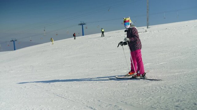 A person in winter gear enjoys skiing down a snowy mountain slope. Experience the thrill of a winter sport at a ski resort under a clear sky.
