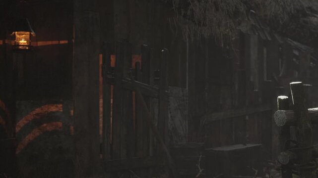 A wooden house with a thatched roof stands in a dim light. A lantern hangs by the entrance. Shadows cover the structure as evening falls. The area is quiet and undisturbed.