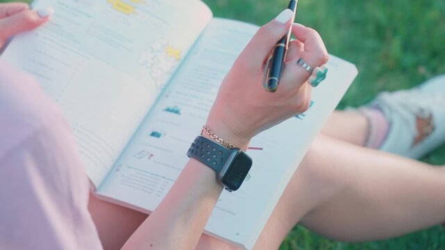 Hands studying German language textbook outdoors in park