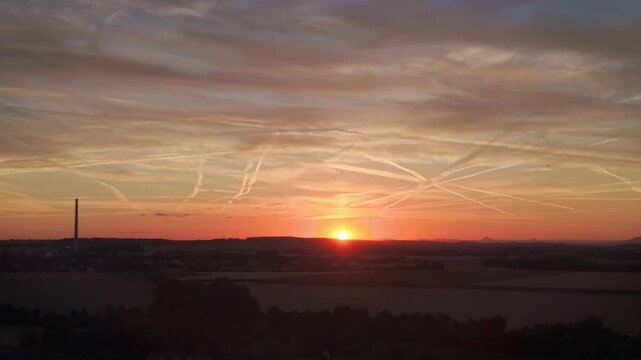 Beautiful sunset over countryside fields with swallows flying in the sky and distant hills