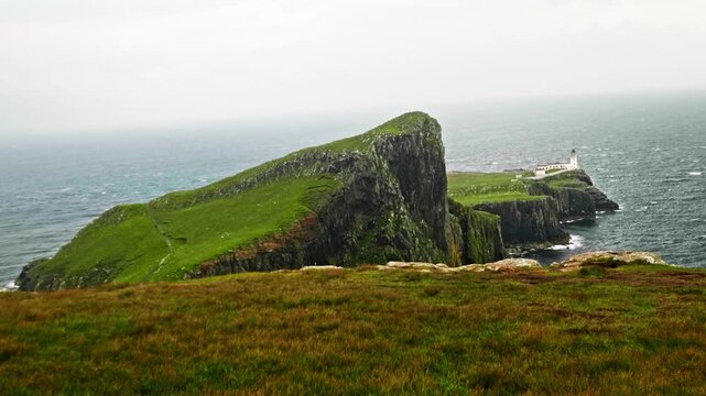 Dramatic neist point lighthouse standing on majestic green cliffs over the sea on a cloudy day. Famous tourist destination in the isle of skye