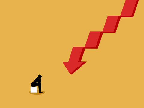 Businessman sit dejectedly watching the graph fall