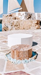 Fototapeta premium Circular wooden dock podium and white pedestal on a stone jetty for coastal product display, featuring weathered textures and sea glass