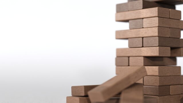 Jenga wooden puzzle tower collapse risk concept for business instability with falling blocks on white background