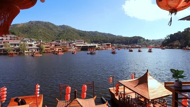 The video of Baan Rak Thai captures traditional Chinese-style boats floating on a tranquil lake, surrounded by mist-shrouded mountains and charming architecture reminiscent of Chinese settlements. It'
