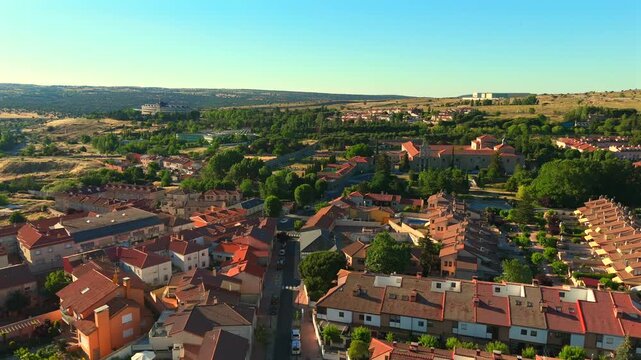 The camera rises above a residential rooftop near Avila, Spain, revealing a green valley beyond.