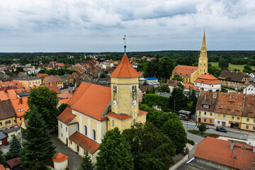 Obraz premium Aerial view of historic Przemkow in Lower Silesia, Poland with medieval town center, Baroque church, colorful buildings with clay tile roofs, surrounding green forests and landscape on sunny day