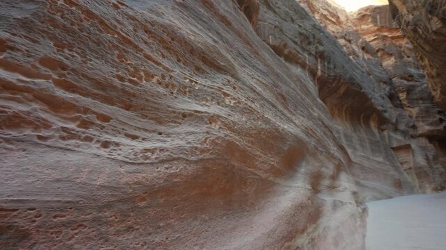 A low angle view of the narrow sandstone canyon walls at the Siq entrance in the ancient city of Petra, Jordan.
