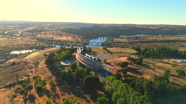 A river bends past a bridge near Avila, Spain, cutting through dry hills and patches of green.