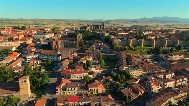 A tightly packed old quarter in Avila, Spain, spreads beneath a church tower and distant mountains.