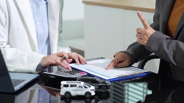 Asian woman uses a calculator to estimate car loan monthly payment, planning budget, finance, credit, and vehicle insurance.