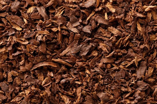 Close-up overhead view of dried, shredded tobacco leaves, creating a rich brown textured background.