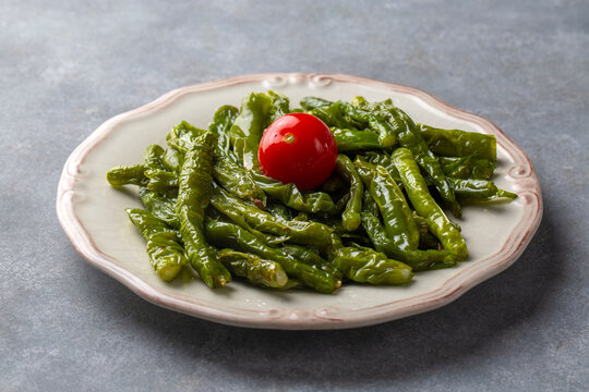 Roasted green friggitello peppers and diced tomatoes served - Turkish name; Biber kizartmasi