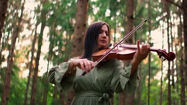 Woman playing violin in tranquil forest setting, creating soulful music among tall trees and natural greenery, expressing emotion through outdoor acoustic performance