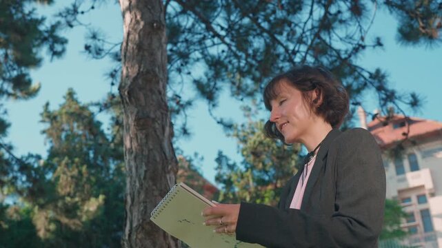 Female artist drawing pencil sketch in sketchbook during outdoor plein air session
