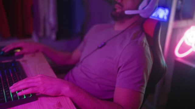 Man wearing headset leans back with eyes closed, one hand on mouse, near neon controller sign in studio; fatigue rest focus.